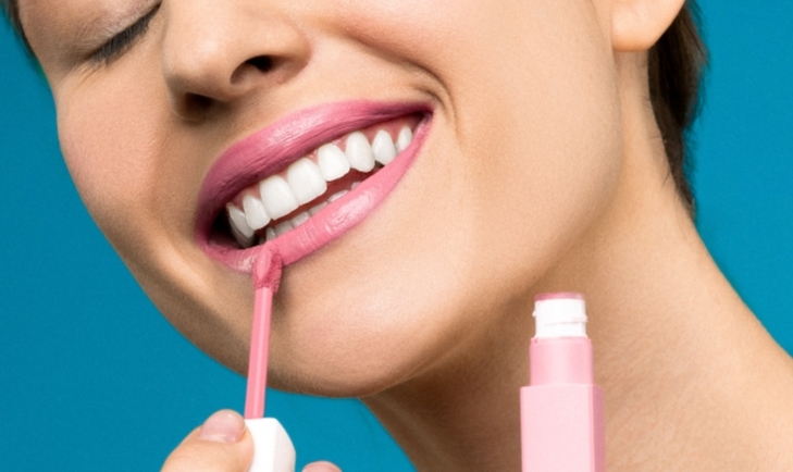Bild einer Frau, die nach einer erfolgreichen Behandlung mit Juvéderm Voluma Lippenstift aufträgt
